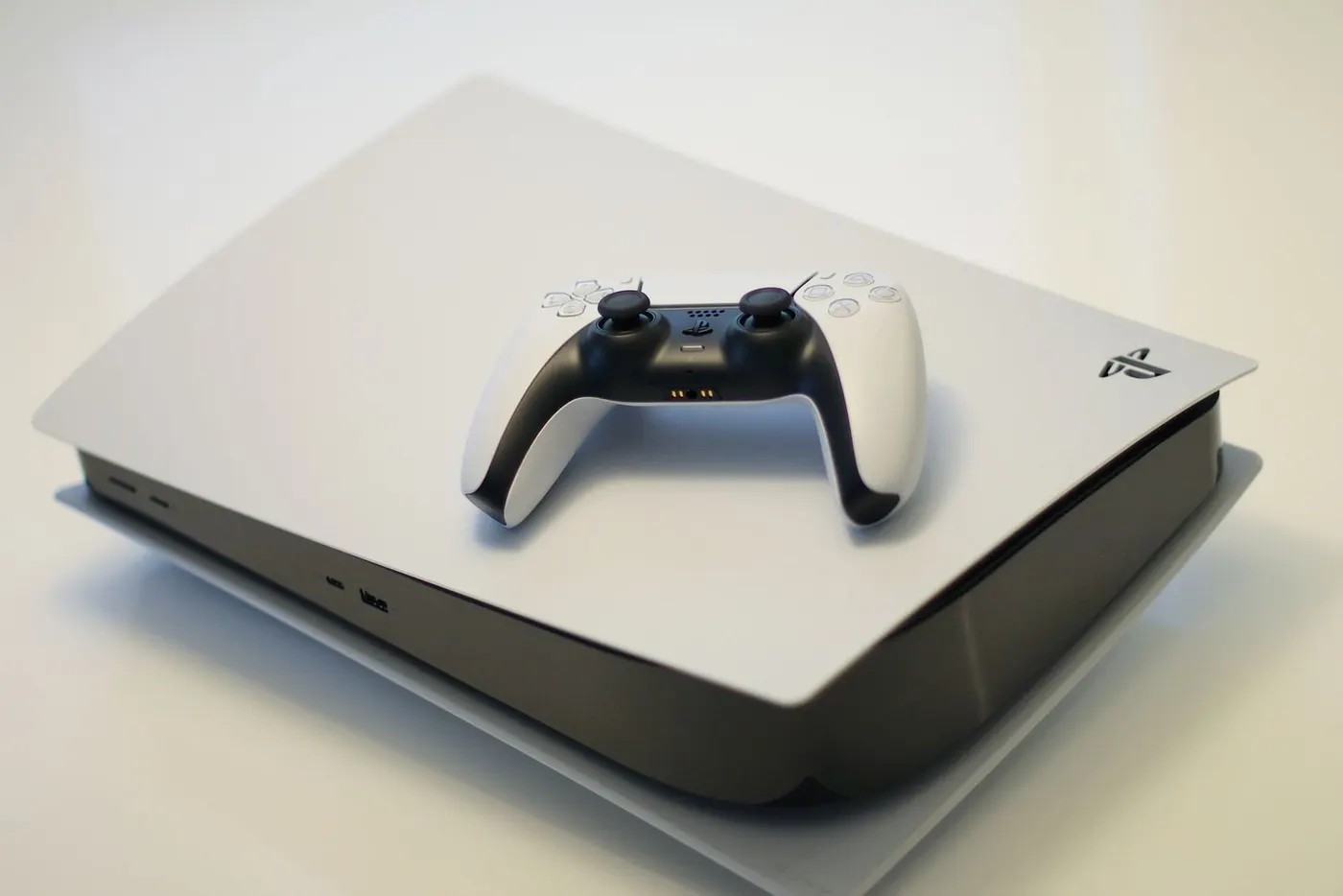 A white PlayStation 5 console with its DualSense controller